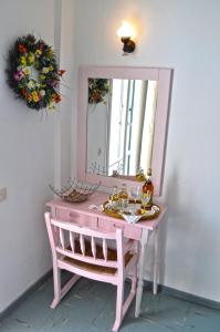 a pink dressing table with a mirror and a chair at Eros Beach Hotel in Benitses
