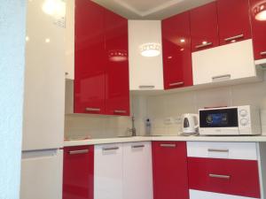 a kitchen with red and white cabinets and a microwave at Apartment on Ivasyuka 11 in Truskavets