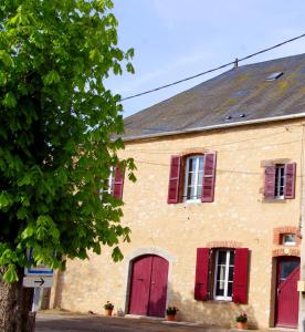 an old brick building with red shuttered windows at Au Foudre du bazois in Châtillon-en-Bazois