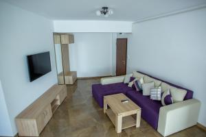 a living room with a purple couch and a table at C&Y Apartments Aqua Park in Mamaia +26 photos