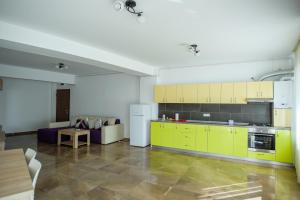 a kitchen with yellow cabinets and a couch at C&Y Apartments Aqua Park in Mamaia