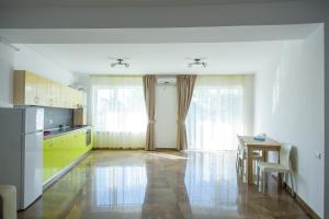 uma cozinha com uma mesa e uma cozinha com armários amarelos em C&Y Apartments Aqua Park em Mamaia