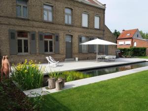 uma casa com piscina e guarda-sol em De Pastorie - Zillebeke em Ypres