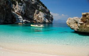 a boat in the water next to a beach at Casa Verde in Cala Gonone