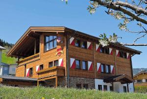 a large wooden building with red and white windows at Dorfstub'n Jochberg in Jochberg