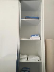 ein Schrank mit weißen Regalen und gefalteten Handtüchern in der Unterkunft White Residence Apartament in Sarandë