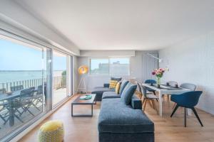 ein Wohnzimmer mit einem Sofa und einem Tisch sowie ein Esszimmer in der Unterkunft Vue sur mer La Baule "Victoria" in La Baule