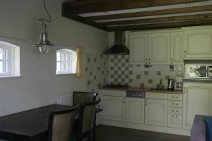 a kitchen with white cabinets and a table and chairs at Vakantiehuis NamaStee in Schoonloo