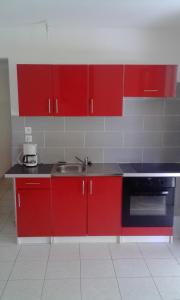 una cocina con armarios rojos y fregadero en villa telyna, en Trois-Rivières