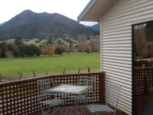 uma mesa e cadeiras num alpendre com vista para um campo em River Terrace Cottage em Motueka