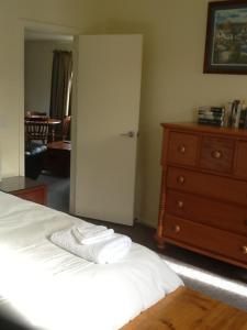a bedroom with a bed and a dresser with towels on it at River Terrace Cottage in Motueka