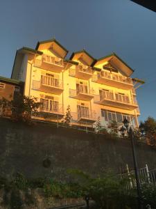 a large yellow building with balconies on top of a wall at Misty Paradise of Lake Gregory in Nuwara Eliya