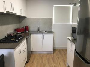 a kitchen with a stove, refrigerator, sink and cabinets at Jesmond Executive Villas in Newcastle