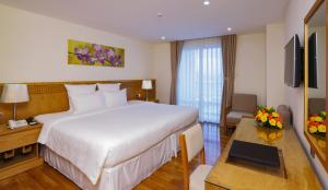 a hotel room with a large bed and a table at Rosaka Nha Trang Hotel in Nha Trang