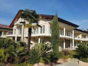 a large white building with palm trees in front of it at De Luxe Apartments Eden in Sirmione