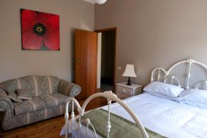a bedroom with a bed and a couch and a red flower at Webster Apartment in Ballarat