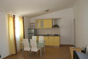 cocina con armarios amarillos, mesa y sillas en Apartments Sara, en Vlašići