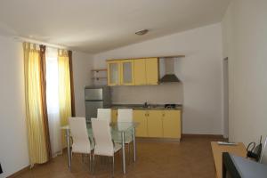 a kitchen with yellow cabinets and a table and chairs at Apartments Sara in Vlašići
