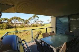 a balcony with a table and chairs and a view of a field at Saltwater Apartments in Eden