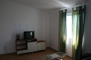 a living room with a tv on a dresser and a window at Apartments Sara in Vlašići