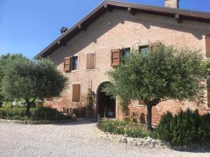 un edificio de ladrillo con árboles delante de él en Agriturismo La Cascinetta en Pieve di Cento