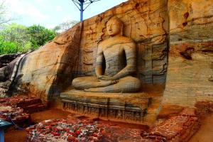 uma grande estátua de pedra no lado de uma parede em Sanctuary Cove Guest House em Polonnaruwa