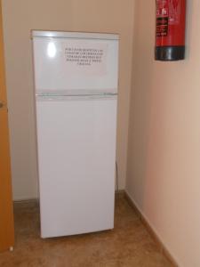 a white refrigerator in a room with a fire extinguisher at La Posada De Sancho in Tomelloso
