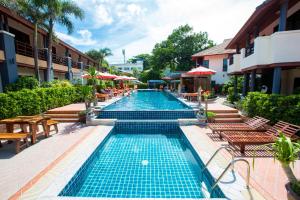 a swimming pool with tables and chairs next to a building at Sunrise Resort- Koh Phangan - SHA Extra Plus in Haad Rin