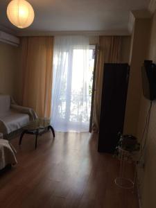 a living room with a couch and a table and a window at Irma Apartment in Batumi