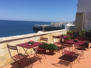 un grupo de mesas y sillas en un patio con vistas al océano en B&B Relais Del Senatore en Polignano a Mare