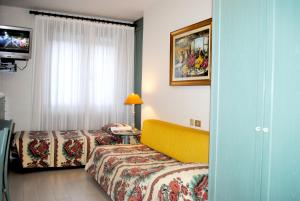 a hotel room with two beds and a television at Residence Antares in Madonna di Campiglio