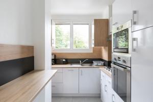 レンヌにあるBrassens by Cocoonrの白いキャビネット、シンク、窓付きのキッチン