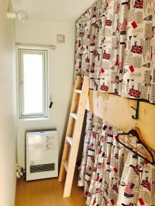 a room with a wall with a curtain and a ladder at Guest House On My Way in Sapporo