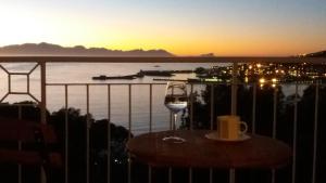 a glass of wine sitting on a table with the sunset at Bayview Heights Gem in Simonʼs Town