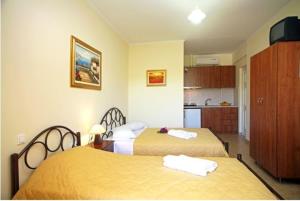 une chambre d'hôtel avec deux lits et une cuisine dans l'établissement Eleana Studios, à Leucade
