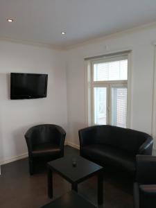 - un salon avec 2 fauteuils en cuir et une télévision dans l'établissement Esplanad Apartment, à Mariehamn