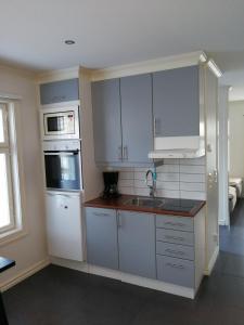 a kitchen with white cabinets and a sink and a microwave at Esplanad Apartment in Mariehamn