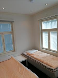 two beds in a room with two windows at Esplanad Apartment in Mariehamn