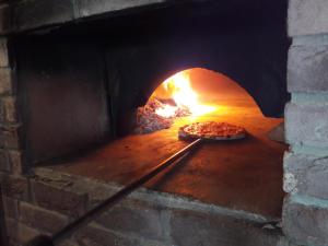 Uma pizza está a ser cozinhada num forno de tijolos. em Apartmani Nikolina Seaview em Sibenik