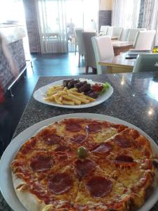 a pepperoni pizza on a table with a plate of fries at Apartmani Nikolina Seaview in Šibenik