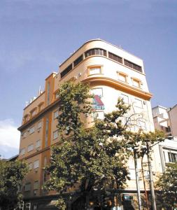 un edificio alto con árboles delante de él en Alcor Hotel en Mendoza