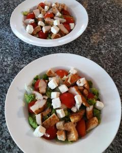 dois pratos de comida com uma salada na mesa em Apartmani Nikolina Seaview em Sibenik