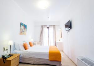 a white bedroom with a bed and a television at Apartment Kalypso in Agia Anna Naxos