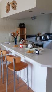 a kitchen with a large white counter with chairs at Bayview Heights Gem in Simonʼs Town