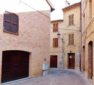 an alley with a brick building and a garage at San Lorenzo in Cerreto dʼEsi