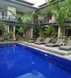 a swimming pool with lounge chairs and a house at Lucky Family Cottage in Ubud