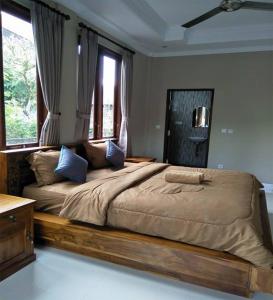 a bedroom with a large bed with blue pillows at Lucky Family Cottage in Ubud