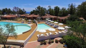 eine Draufsicht auf einen Resort-Pool mit Stühlen und Sonnenschirmen in der Unterkunft Tiliguerta Glamping&Camping Village in Costa Rei