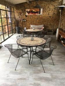 un patio con mesas y sillas y una pared de ladrillo en Chambres D'Hôtes Les Boudines, en Saint-Germain-de-Belvès