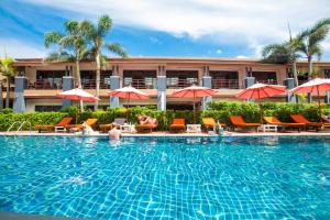 a pool with chairs and umbrellas in front of a hotel at Sunrise Resort- Koh Phangan - SHA Extra Plus in Haad Rin